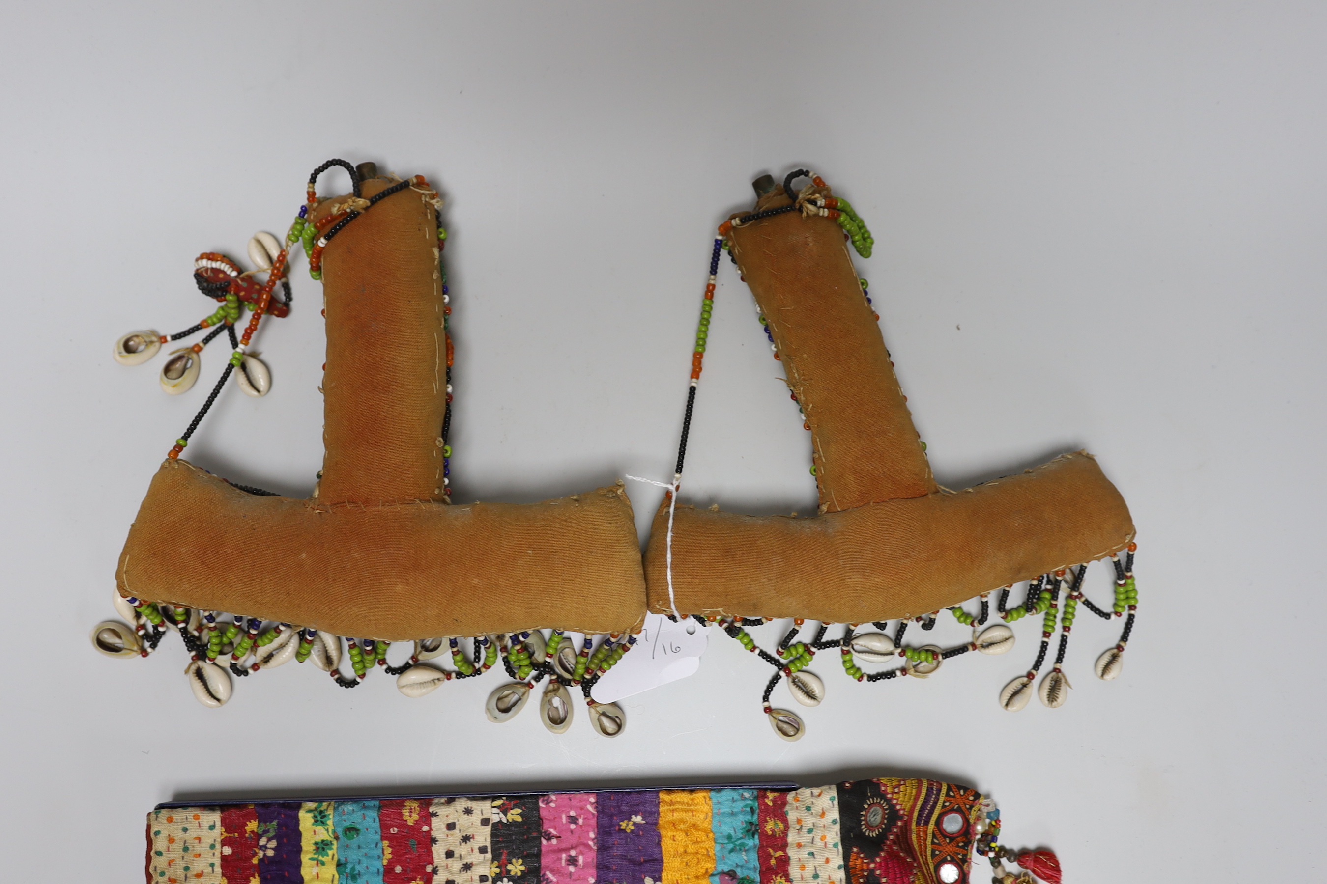 19th and 20th century textiles: An Indian mirrored and patchwork bag, a smaller embroidered bag, an ‘arrow’ shaped mirrored panel and two Omani shell and beaded ‘anchor’ shaped hangings, ‘arrow’ hanging 45cm long (5)